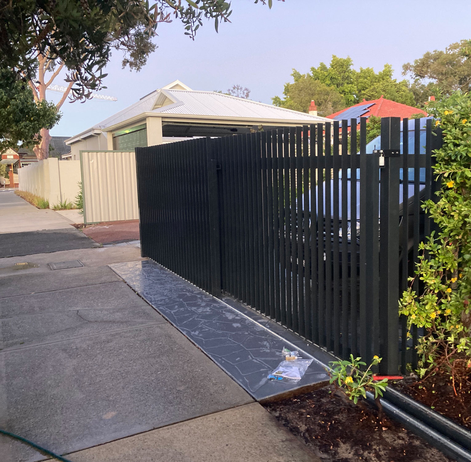 Aluminium Double Flat Bar Blade Electric Telescopic Vehicle Gate with Fence Panels. Constructed of 50 x 10mm Flat Bar Aluminium face Welded with 100mm Gaps. Aluminium Powdercoated in Charcoal Gloss. Automated with the Centsys D5 Evo Low Voltage Gate Motor Kit. Contact Western Automate today for a free, no-obligation quote - 08 6499 2812 | sales@westernautomate.com.au | https://westernautomate.com.au